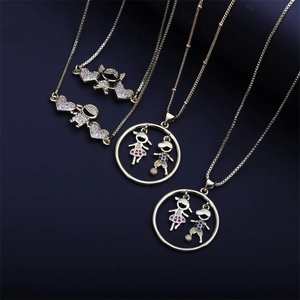 Detail of gold necklaces featuring crystal-studded boy and girl pendants on dark background