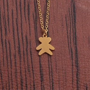 Polished gold titanium steel bear pendant necklace shown on a textured brown background