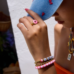 Nahaufnahme von bunten Tonperlen und 18K Gold-Edelstahl-Armbändern an einem Modell