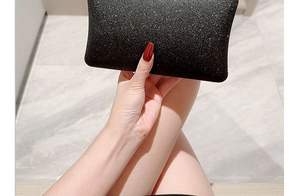 Close-up of elegant black evening clutch bag held by hand in a formal party setting