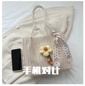 Detail of woven tote bag with floral charm and scarf showing large capacity for smartphone