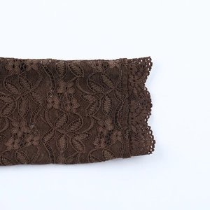 Détail de tissu en dentelle marron foncé avec motifs de feuilles et bord festonné