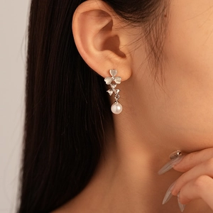 Détail de boucles d'oreilles fleurs en œil de chat et perles portées par un mannequin