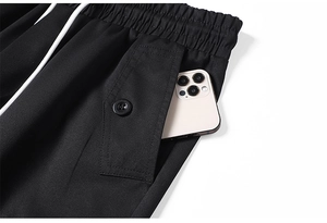 Dettaglio dei pantaloni neri con elastico in vita, coulisse e tasca cargo con bottone