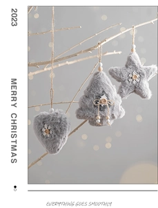 Detail of gray plush heart, star, and tree ornaments hanging on white branches