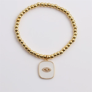 Detail of gold beaded stretch bracelet with white enamel evil eye charm and zircons