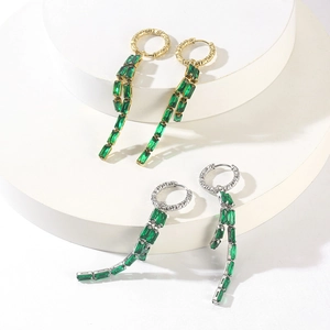 Detail of 18K gold and silver tassel earrings with green rectangular emerald stones