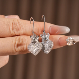 Gros plan macro de boucles d'oreilles cœur couronne en argent avec zircons étincelants