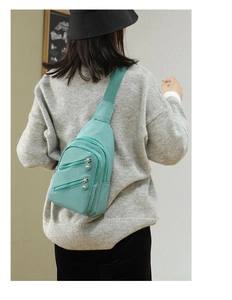 Rear view of model wearing a light green nylon crossbody chest bag with zipper pockets