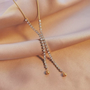 Elegant gold double tassel Y-shaped necklace with rhinestones on silk background
