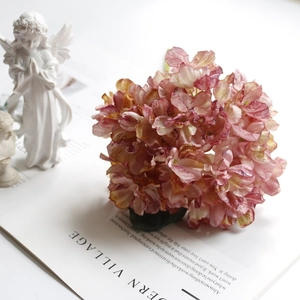 Detailed view of vintage coral hydrangea silk flowers on a magazine with angel statues