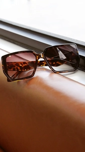 Detailed view of oversized tortoiseshell sunglasses with brown gradient lenses on leather