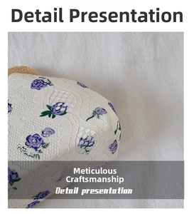 Close-up of white lace fabric with purple rose embroidery on a stylish summer shell bag