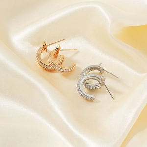 Close-up of gold and silver half-hoop earrings with cubic zirconia on silk fabric