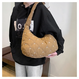 Braune gesteppte Hobo-Tasche mit weißem Schleifenmuster am Modell für Größe und Stil