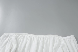 Dettaglio del top bianco con spalle scoperte e trama plissettata elegante sullo scollo