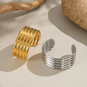 Detail shot of multi-layer striped open bangles in gold and silver finish on stone