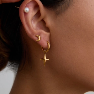 Close-up of elegant gold stud earrings with pearls and moon charm on model's ear