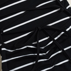 Macro detail of ribbed knit striped dress featuring an elegant back tie-up bow closure