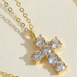 Macro shot of 14K gold plated cross pendant necklace with six sparkling zircon stones