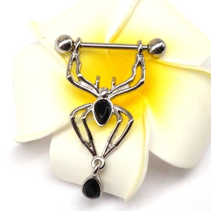 Piercing téton araignée argentée avec pierres noires en poire sur fond de fleur