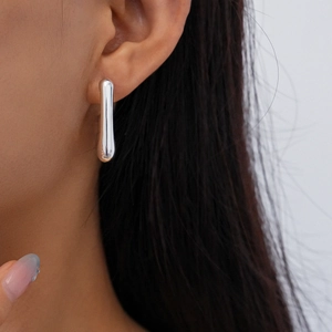 Close-up of minimalist silver water drop earring worn by a model in a high-detail shot