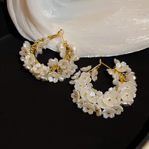 Elegant C-shaped hoop earrings featuring white pearl flower clusters and golden metal accents