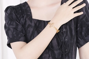Detail of gold chain bracelet with sparkling zircon-paved cross and toggle clasp