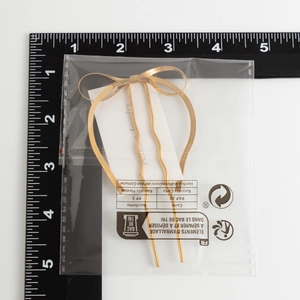 Macro shot of a golden metal alloy bow hair clip on a measuring ruler for size scaling