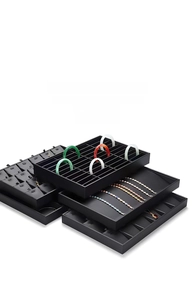 Macro detail of black stackable jewelry tray with rings, bracelets and necklace slots