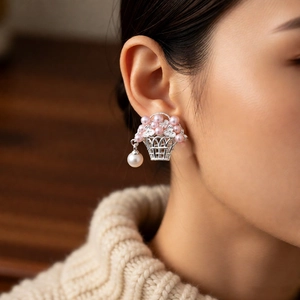 Détail de boucles d'oreilles panier en argent avec perles roses et gouttes blanches
