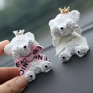 Close-up of white teddy bear car air fresheners with gold and silver crowns