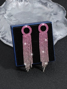 Detailed macro view of pink rhinestone tassel earrings hanging on blue jewelry box
