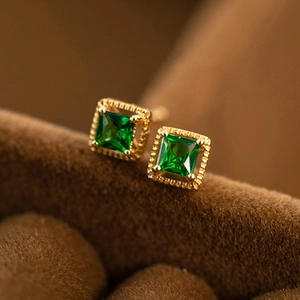 Classic gold square stud earrings with green zircon stones on brown velvet background