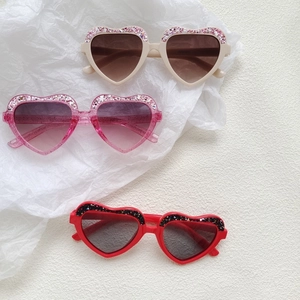 Glittery heart-shaped kids sunglasses in beige, pink and red with gradient lenses