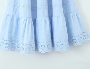 Détail de robe longue en coton bleu clair avec volants étagés et broderie ajourée