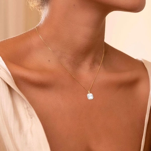 Close-up of elegant gold S925 silver necklace with cushion-cut zircon pendant on collarbone