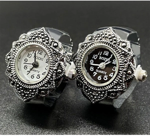 Close-up of vintage quartz ring watches with black and white dials and silver floral cases
