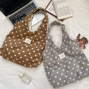 Close-up of brown and grey polka dot corduroy tote bags on a cozy white fabric setting