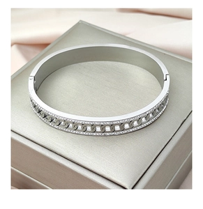 Macro detail of silver bangle with cubic zirconia pave and curb link cutout design