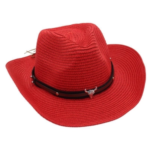 Detail of red straw cowboy hat with metallic bull head emblem and studded leather band