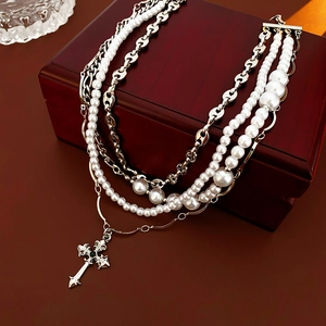 Close-up of layered necklace with pearls and cross pendant on a wooden display box