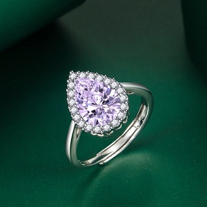 Macro detail of pear-cut purple gemstone ring with sparkling zircon halo and silver band