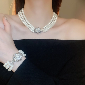 Parure collier et bracelet à trois rangs de perles avec fermoir fleur argentée sur mannequin