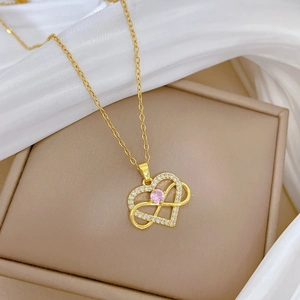 Detail of gold heart and infinity necklace with pink center stone on silk