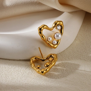 Macro shot of gold heart studs with irregular lava texture, pearls, and crystal stones