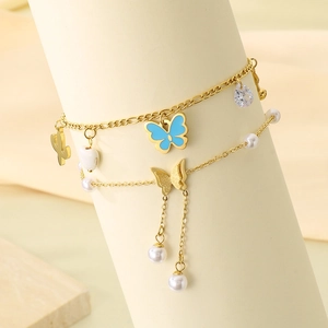 Close-up of double-layer gold anklet featuring blue enamel butterfly and pearl charms