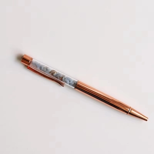 Macro detail of rose gold crystal ballpoint pen with blue and grey stone fillings