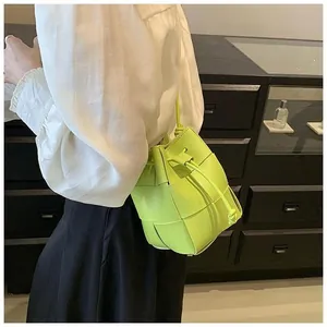 Detail of neon green woven leather mini bucket bag featuring drawstring closure and slim strap