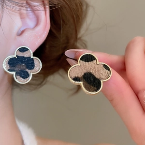 Close-up of leopard print clover earrings with gold metal edges on model and in hand